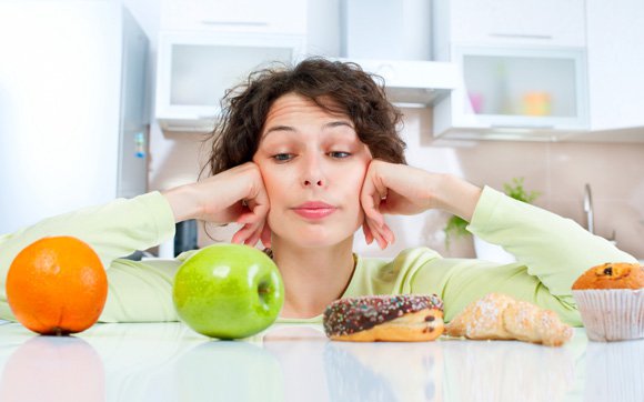 Woman Making a Choice Between Fruit and Junk Food